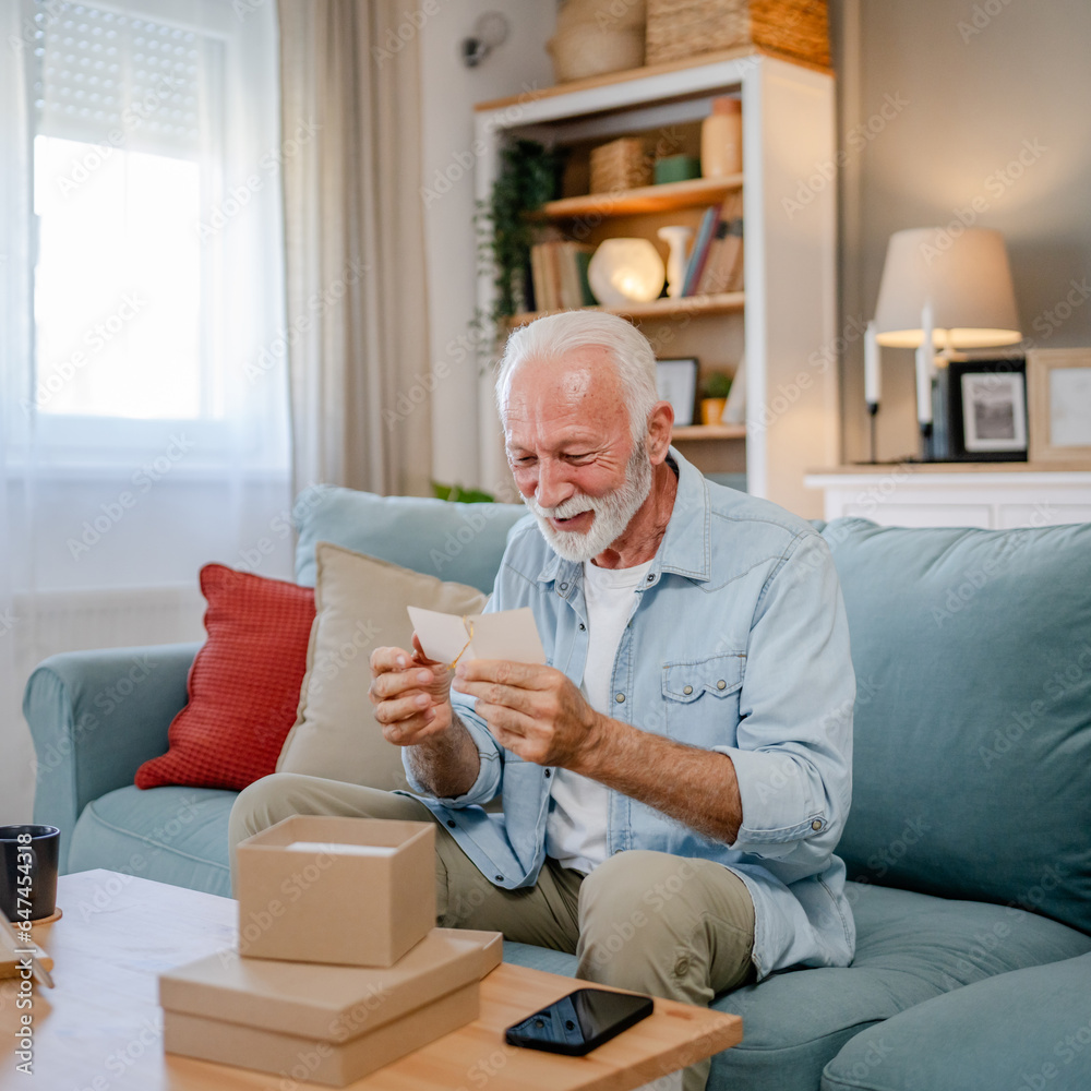 one senior man open box presents and read card while on video call one senior man open box presents and read card while on video call