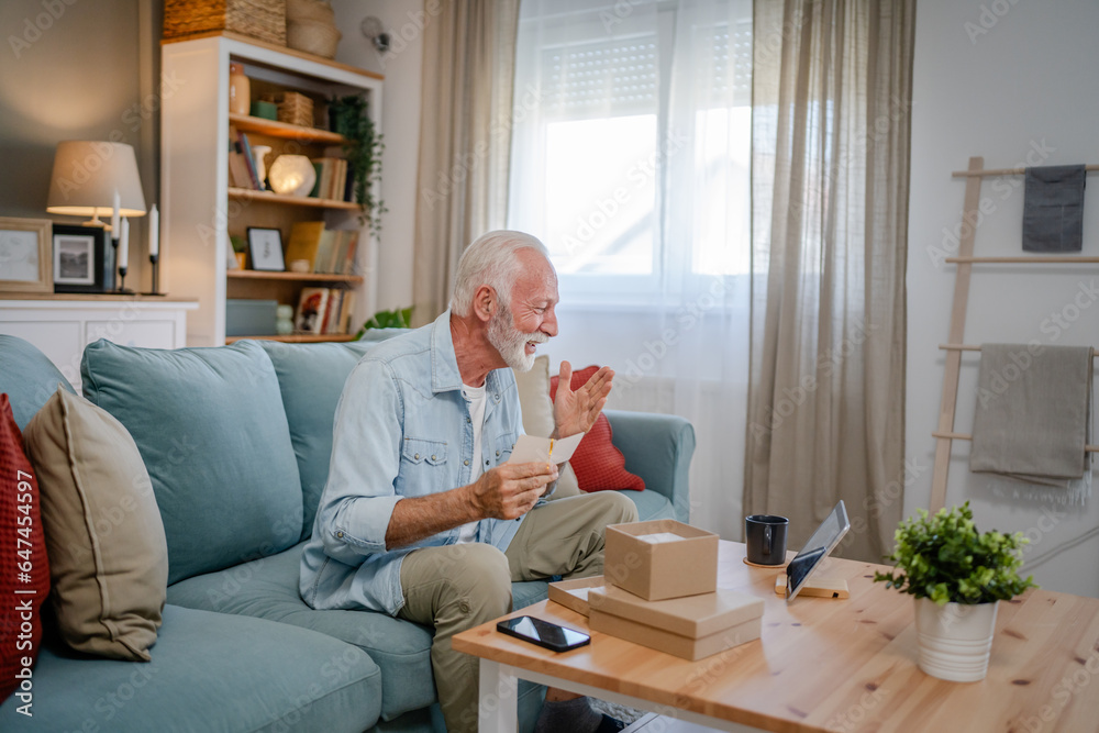 one senior man open box presents and read card while on video call one senior man open box presents and read card while on video call