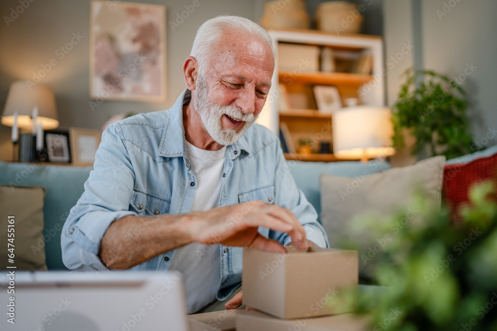 one senior man open box presents and read card while on video call