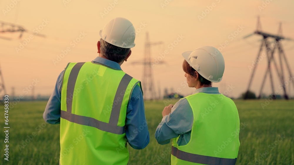 Business people, power construction. Two energy engineers work with computer tablet outdoors