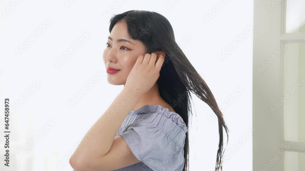 風にロングヘアをなびかせる若い女性 風にロングヘアをなびかせる若い女性