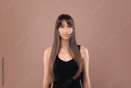 Hair styling. Portrait of beautiful woman with straight long hair on pale brown background