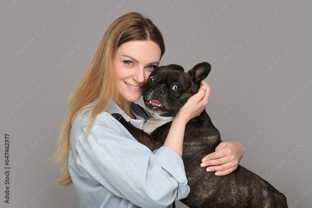 Portrait of happy woman hugging cute French Bulldog on grey background Portrait of happy woman hugging cute French Bulldog on grey background