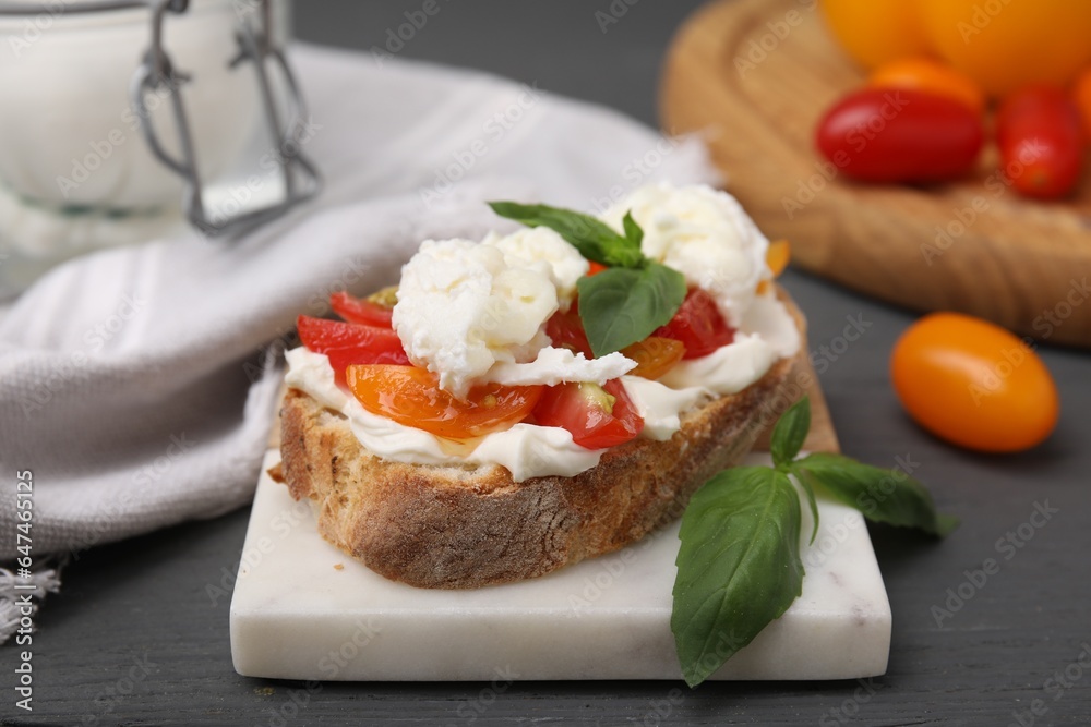 Delicious sandwich with burrata cheese and tomatoes on grey wooden table, closeup