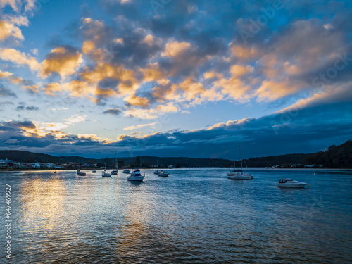Aerial sunrise waterscape with boats and scattered rain clouds