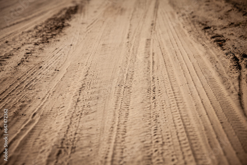Selective blur on a tire track on a sand, traces of tyres and wheels of cars and vehicles driving off road on a dirt path, a sandy trail on a beach or a desert.
