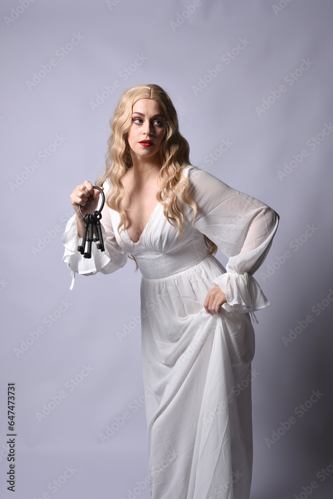 Close up portrait of beautiful blonde model wearing elegant white halloween gown, a historical fantasy character. Holding old key chain, isolated on studio background. Close up portrait of beautiful blonde model wearing elegant white halloween gown, a historical fantasy character. Holding old key chain, isolated on studio background.