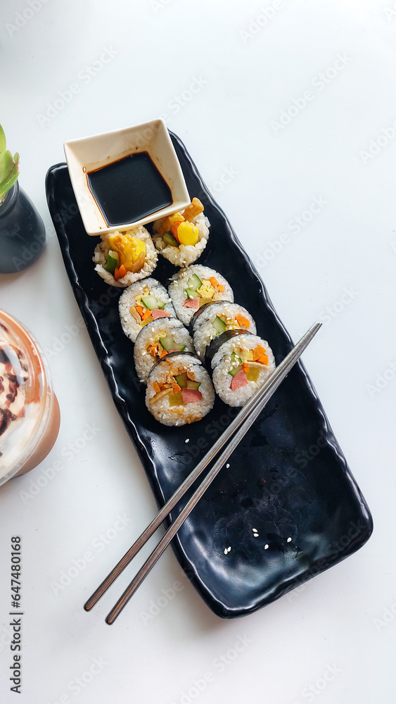 Overhead vertical view of gimbap roll served in a black long plate, a popular traditional authentic South Korean dish Overhead vertical view of gimbap roll served in a black long plate, a popular traditional authentic South Korean dish