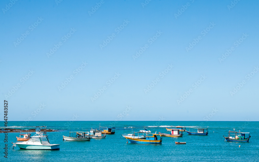 beach with boats in the sea with blue sky and space for text