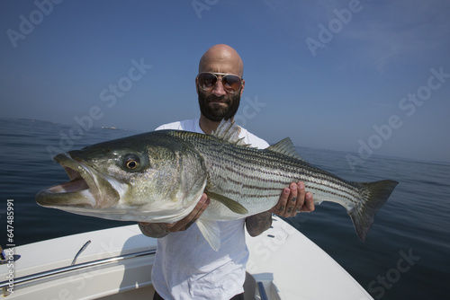 Fisherman Holding A Large Striper Fish, Boston Harbour; Boston, Massachusetts, United States Of America