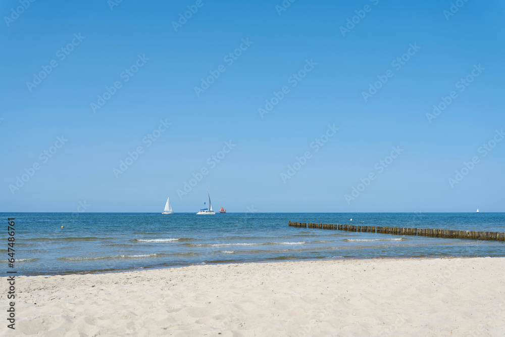 Strand bei Kühlungsborn an der deutschen Ostsee mit blauem Himmel und einigen Segelbooten am Horizont 