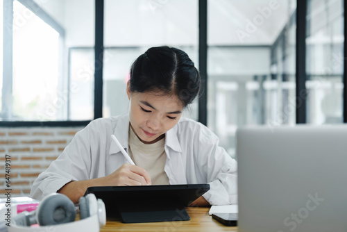 Young collage student using computer and mobile device studying online...