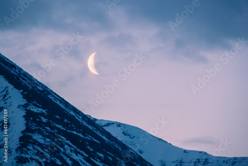 The crescent moon sets above the sentinal range along the alaska highway, muncho lake provincial park, northern canadian rockies; British columbia, canada photo