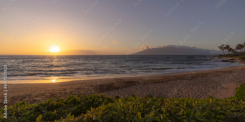 View of Pacific Ocean and golden sun at twilight from the sandy shore of Keawakapu Beach; Kihei, Wailea, Maui, Hawaii, United States of America View of Pacific Ocean and golden sun at twilight from the sandy shore of Keawakapu Beach; Kihei, Wailea, Maui, Hawaii, United States of America