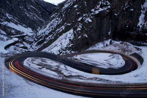 Car lights blur on a switchback road above San Gotthard tunnel in Switzerland; Andermatt, Switzerland