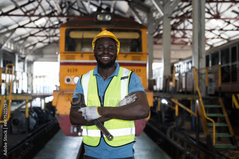 African American male engineer working with happy and smile in in locomotive repair garage. Portrait of male railway engineer repair train wheel in train garage African American male engineer working with happy and smile in in locomotive repair garage. Portrait of male railway engineer repair train wheel in train garage