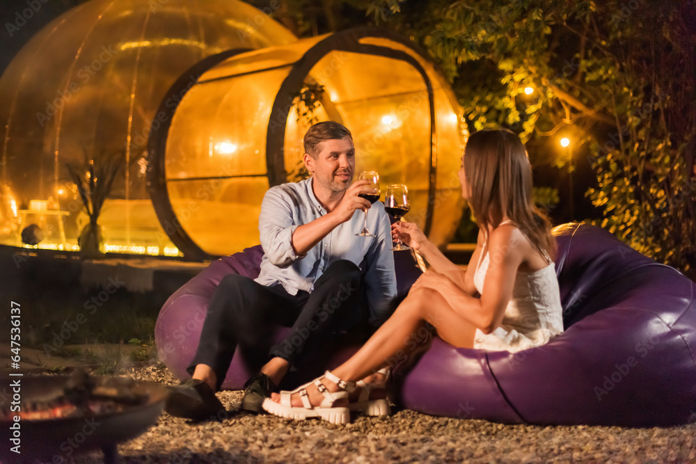 Couple drinking wine at glamping at night
