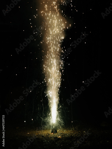 fountain of sparks and smoke bursting out of a diwali flower cone fire cracker at night during a festival