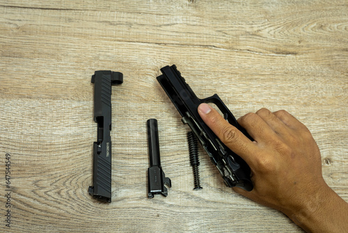 Parts of an automatic pistol on a wooden table background.