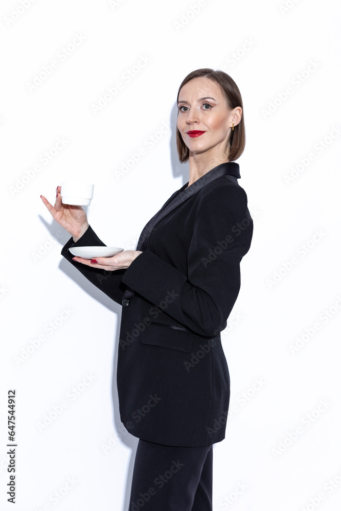 Cute Winsome Positive Confident Caucasian Business Woman in Black Suit Posing With Coffee Tea Cup Over White Cute Winsome Positive Confident Caucasian Business Woman in Black Suit Posing With Coffee Tea Cup Over White