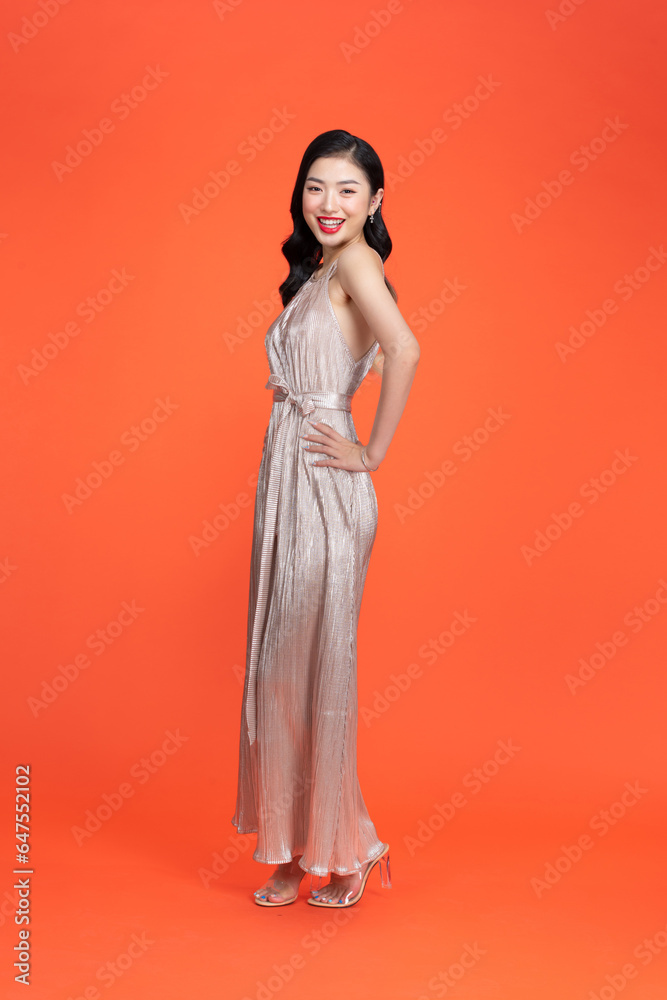 Attractive girl in shiny silver dress and high heels smiles on red background. Attractive girl in shiny silver dress and high heels smiles on red background.