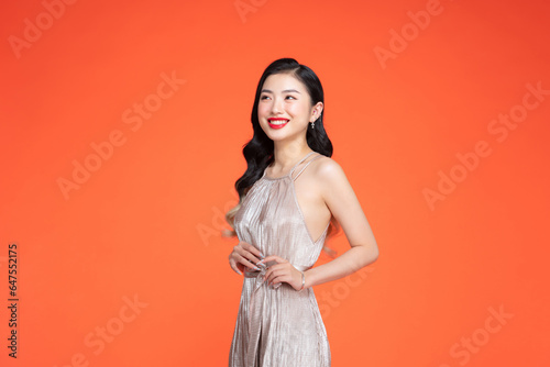 female posing in long golden party dress over red background