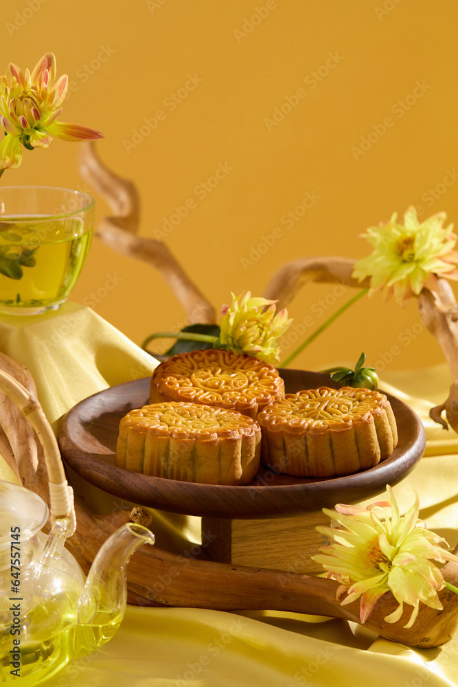 Front view of Chinese Festival dessert on yellow fabric plate, decorated with flowers and tree branches. A transparent tea set featured. Minimalist style tea party table Front view of Chinese Festival dessert on yellow fabric plate, decorated with flowers and tree branches. A transparent tea set featured. Minimalist style tea party table