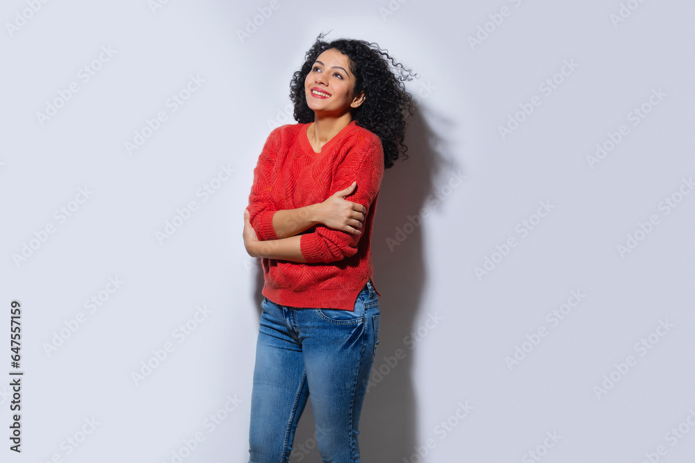 Young woman in red sweater standing with crossed hands and looking away Young woman in red sweater standing with crossed hands and looking away