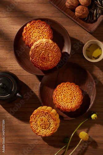 Top view of some traditional mooncakes placed on round wooden dishes. A dish of walnuts and sunflowers seeds. Chinese traditional festival