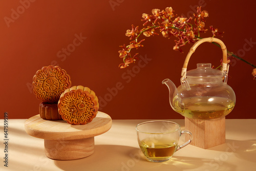 Over dark red background  Mooncake Yolk Pastry displayed with a transparent tea set. Captivating Visual Journey through the Traditions of the Mid-Autumn Festival in China