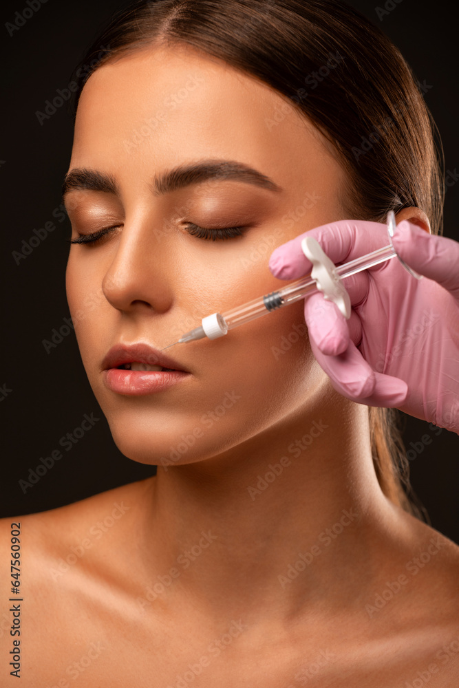 Obraz premium Cosmetologist does injections for lips augmentation and anti wrinkle in the nasolabial folds of a beautiful woman. Women's cosmetology in the beauty salon.