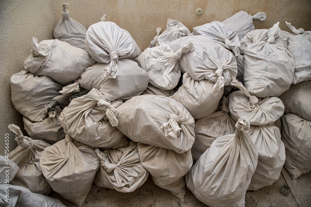 Obraz premium Sealed white sugar bags, full of garbage for disposal, located inside apartment.