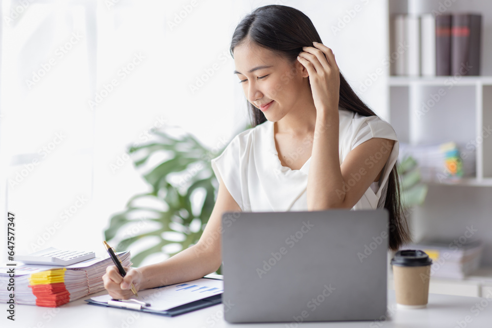 Happy young Asian girl working at a office with a laptop calculator to calculate business accounting statistics concept Happy young Asian girl working at a office with a laptop calculator to calculate business accounting statistics concept