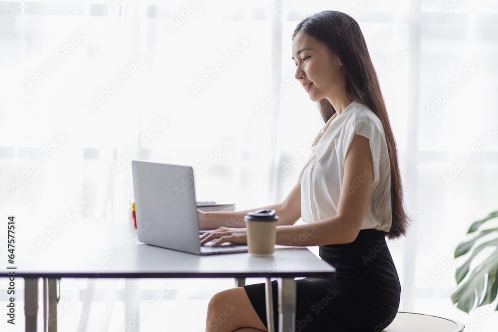 Happy young Asian girl working at a office with a laptop calculator to calculate business accounting statistics concept Happy young Asian girl working at a office with a laptop calculator to calculate business accounting statistics concept