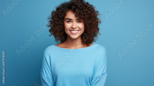 Charming cheerful young woman demonstrating advertising copy, blank space, bright blue background. © sirisakboakaew
