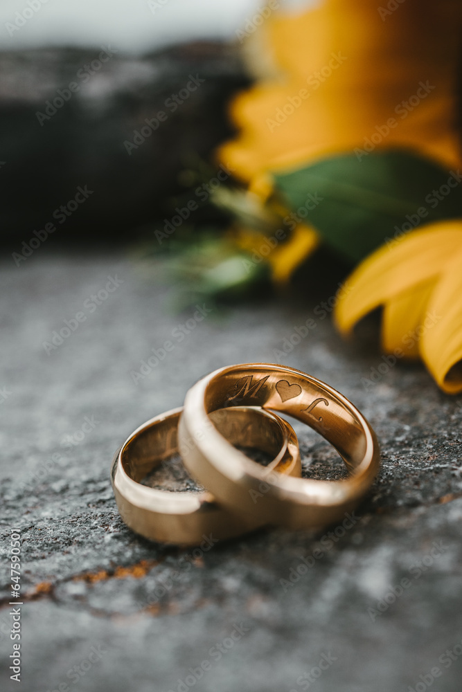 Wedding rings on the stone with a sunflower on the background Wedding rings on the stone with a sunflower on the background