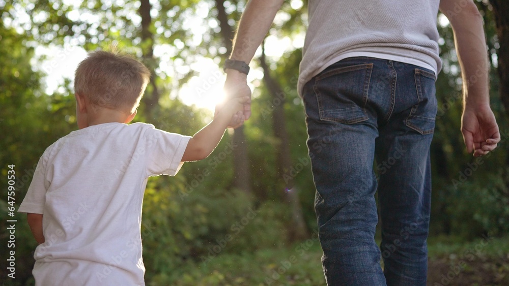 father and son in the park. dad walks with the baby in the forest park holds the hand the glare of the sun in the summer. happy family kid dream concept. father and baby walk in nature in fun the park father and son in the park. dad walks with the baby in the forest park holds the hand the glare of the sun in the summer. happy family kid dream concept. father and baby walk in nature in fun the park