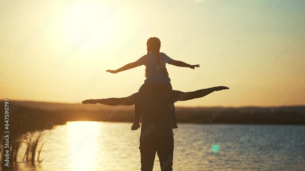 Father and daughter. daughter sits on dads neck silhouette in a field in the park. happy family childhood dream concept. father and daughter play pilots , dreaming of showing fun lifestyle the plane