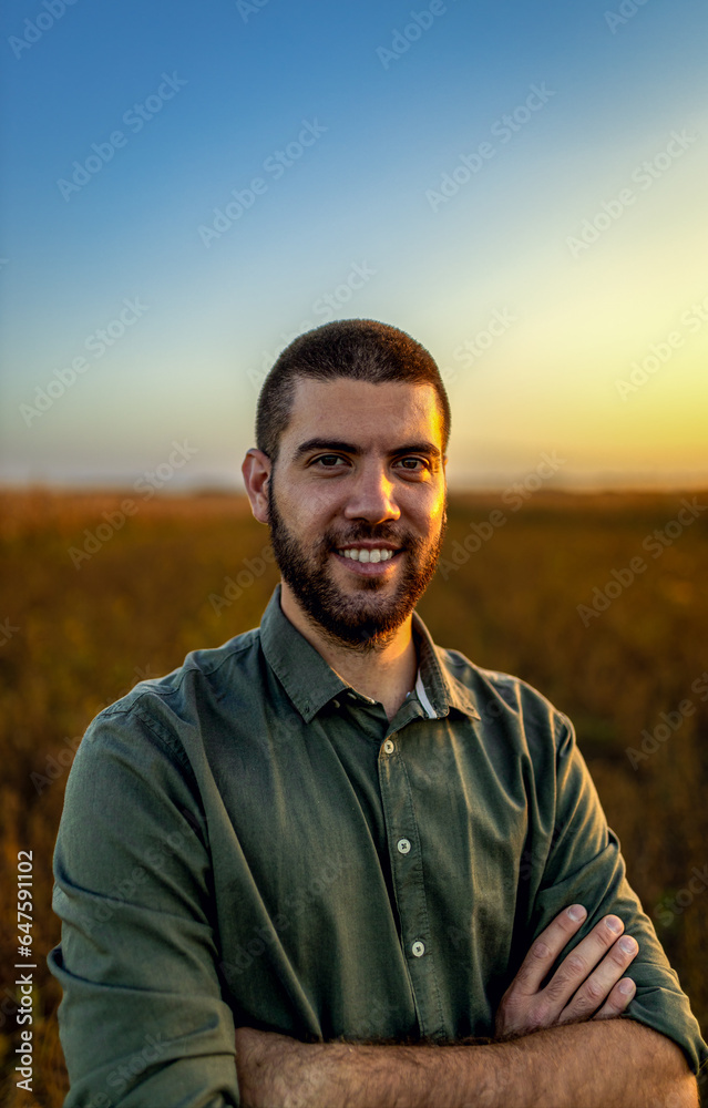 Portrait of young farmer standing in a soy field at sunset looking at camera. Portrait of young farmer standing in a soy field at sunset looking at camera.
