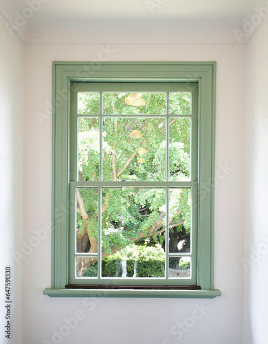 Window with a view of the greenery of the garden surrounded by white walls in the room
