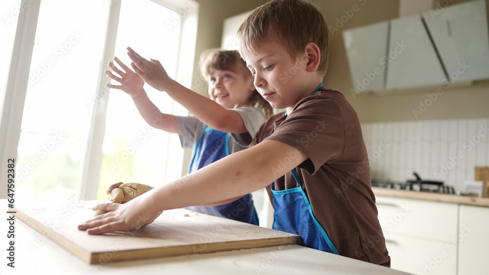 Fototapeta premium children kids making dough in the kitchen. baby boy cook in the kitchen knead dough and flour lifestyle indoors. happy family kid dream concept. bake children play cooking dough together at home