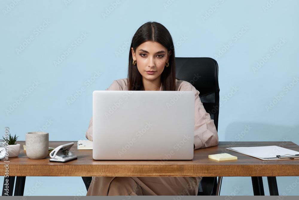 young businesswoman sitting on chair at table and using laptop young businesswoman sitting on chair at table and using laptop