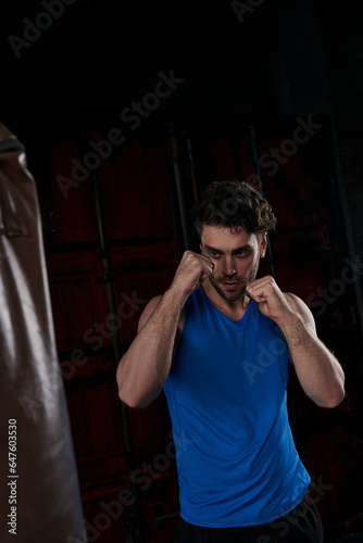 strong man in blue tank top boxing punching bag at night in city, street workout photo