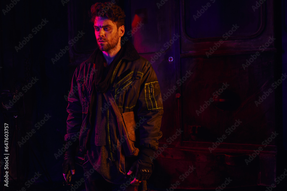 despaired unshaven man in worn clothes standing in dark post-apocalyptic subway with red light despaired unshaven man in worn clothes standing in dark post-apocalyptic subway with red light
