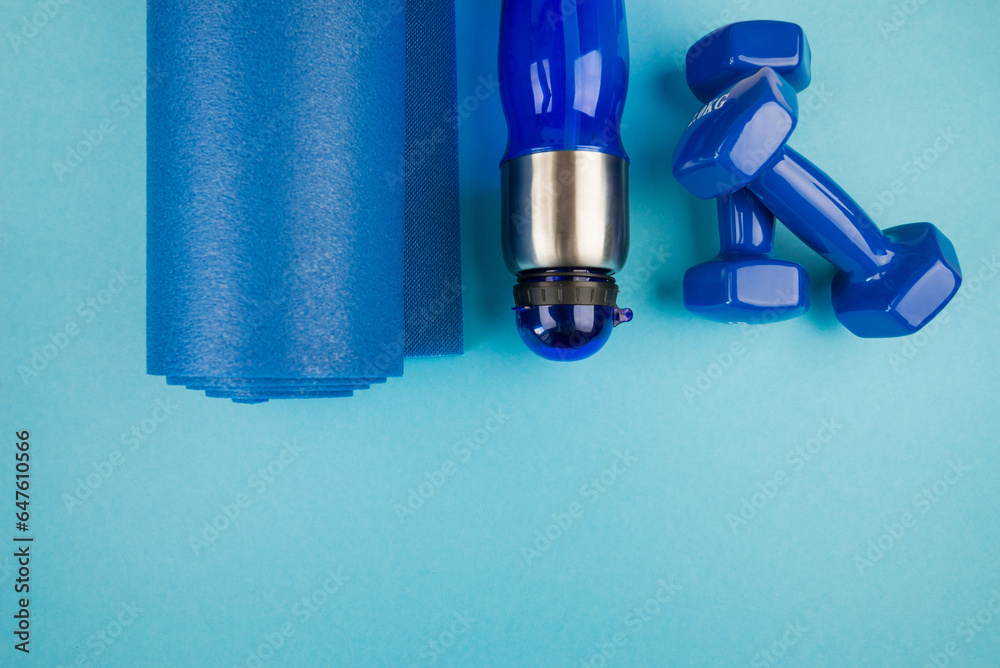 Top view of blue dumbbell bottle and fitness mat Top view of blue dumbbell bottle and fitness mat