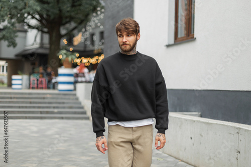 Fotografia Fashionable handsome hipster man with a beard and tattoo in a black stylish mock