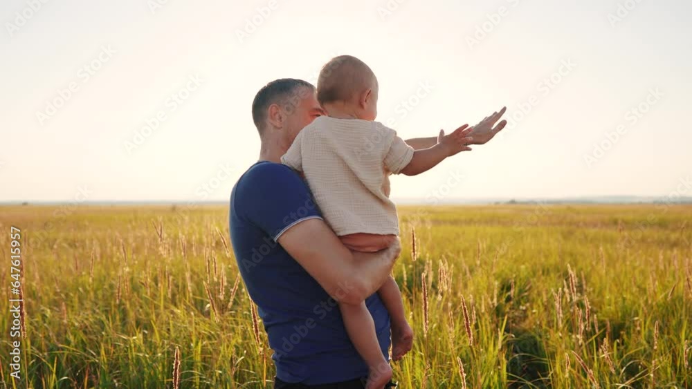 father with son in his arms in a clearing in nature. happy family childhood dream concept. parent holding son in arms in a meadow with tall grass. dad and baby lifestyle in the foreground sunset father with son in his arms in a clearing in nature. happy family childhood dream concept. parent holding son in arms in a meadow with tall grass. dad and baby lifestyle in the foreground sunset