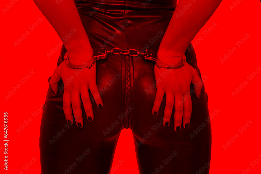 Sexy dominatrix hands on ass in handcuffs in red light, bdsm. - obrazy, fototapety, plakaty 