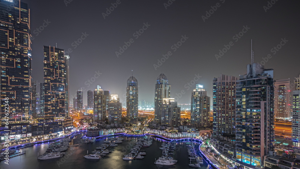 Panorama showing Dubai marina tallest skyscrapers and yachts in harbor aerial night timelapse.