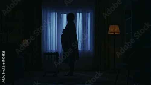 Everyday life creative concept. Woman covered in plaid stands next to heater in the room.